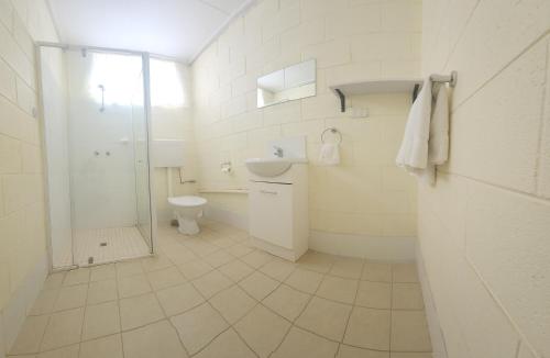 a white bathroom with a toilet and a shower at Broken Hill Hotel in Boulder