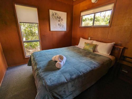 a teddy bear sitting on a bed in a bedroom at Gumnut Glen Cabins in Yeppoon