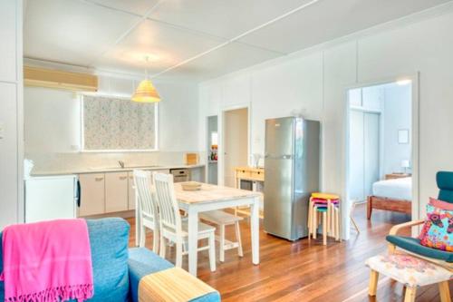 eine Küche und ein Wohnzimmer mit einem Tisch und einem Kühlschrank in der Unterkunft Sandy Feet Cottage in Bargara