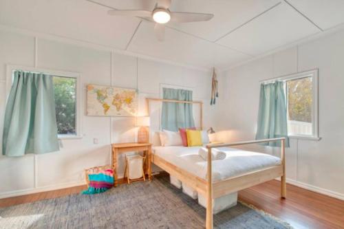 a bedroom with a bed and two windows at Sandy Feet Cottage in Bargara