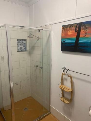 a bathroom with a shower and a painting on the wall at Sandy Feet Cottage in Bargara