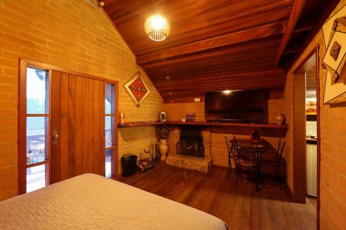 a bedroom with a fireplace and a television and a bed at Chalés Araucária e Manacá in São Bento do Sapucaí