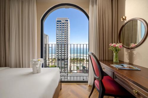 Habitación con cama, escritorio y ventana. en Golden Lotus Luxury Hotel Danang, en Da Nang