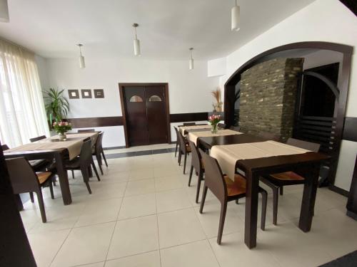 a dining room with tables and chairs and a fireplace at Pensiunea Rodis in Moieciu de Sus