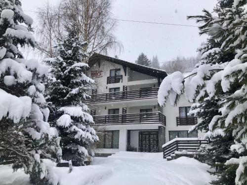 a building covered in snow with snow covered trees at Pensiunea Rodis in Moieciu de Sus