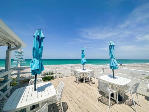 恩格爾伍德的住宿－The Pearl Beach Inn，海滩上的两张桌椅和遮阳伞