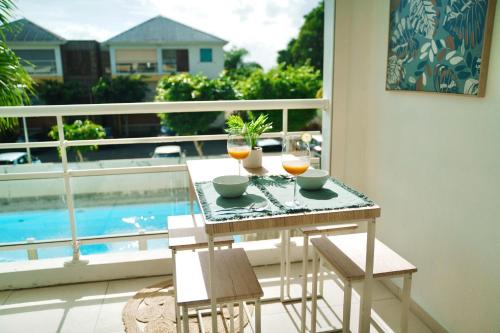 a table with two glasses of orange juice on a balcony at Appartemment T2 cosy et spacieux : l’Oasis urbaine in Les Abymes