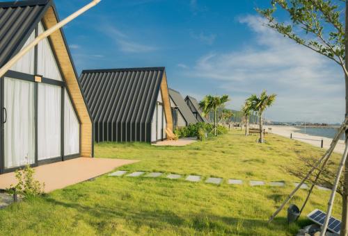 a row of houses on the beach with palm trees at Summer Bay Beach Club & Cabins Sihanoukville by Preference in Sihanoukville