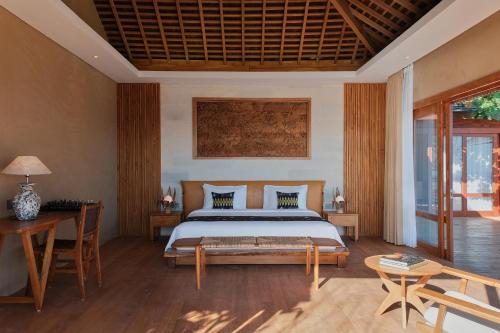 BumbangにあるTUNAK Resort Lombokのベッドルーム1室(ベッド1台、テーブル、椅子付)