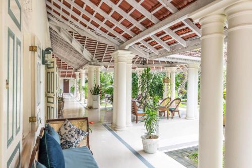 an outdoor patio with columns and chairs and a porch at The Sun House in Galle