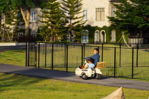 a woman riding a toy car with a child on it at Thames Valley Khao Yai - SHA Plus in Mu Si