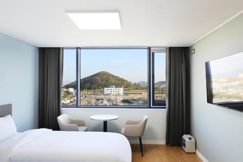 a hotel room with a bed and a large window at Mokpo Ocean Hotel in Mokpo