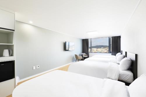 a hotel room with two white beds and a window at Mokpo Ocean Hotel in Mokpo