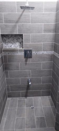 y baño con ducha de azulejos grises. en Ihola's Nest en Carriacou