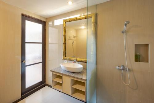 a bathroom with a sink and a shower with a mirror at Canggu Spirit Guest House in Canggu