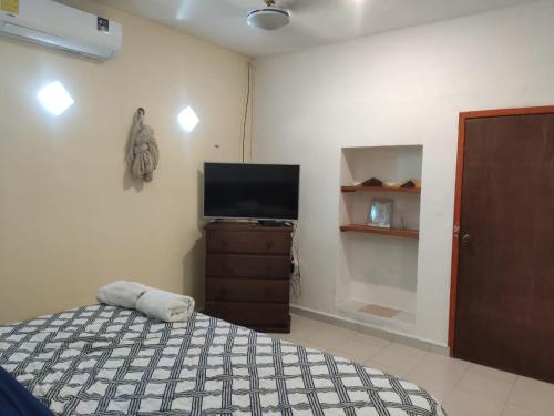 a bedroom with a bed and a flat screen tv at Corazón Abierto in Chicxulub