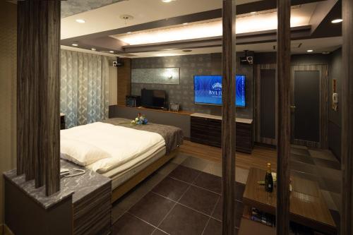 a bedroom with a bed and a flat screen tv at ホテル ブルジュア 久留米 Hotel Bvljua -レジャーホテル- in Kurume