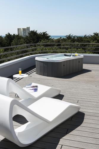 une terrasse avec des chaises longues blanches et un bain à remous dans l'établissement Hôtel Valdys Thalasso & Spa - les Pins, à Saint-Jean-de-Monts