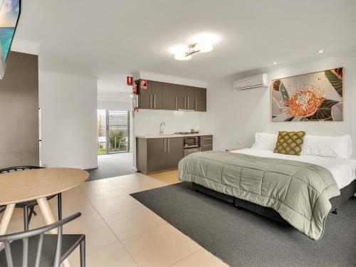 a bedroom with a bed and a table and a kitchen at BIG4 Ingenia Holidays Queenscliff Beacon in Queenscliff