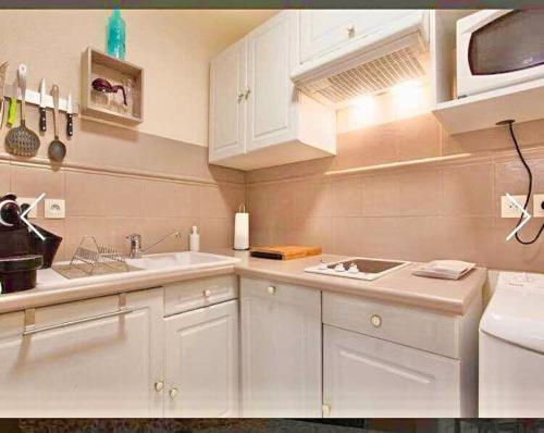 une cuisine avec des armoires blanches et un évier dans l'établissement Appartement Canne 1 chambre - 52C, à Cannes