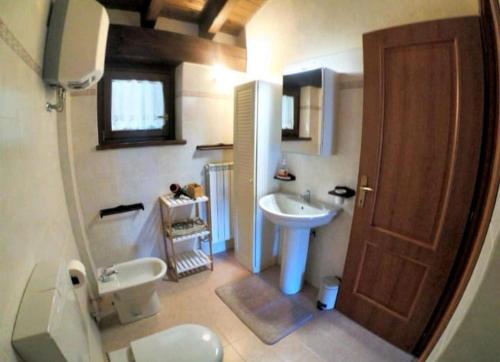 łazienka z toaletą, umywalką i drzwiami w obiekcie Casa Le Petit Bijou w mieście Champoluc