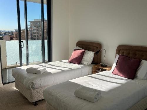 two beds in a room with a large window at Hurstville New apartment with city view in Sydney