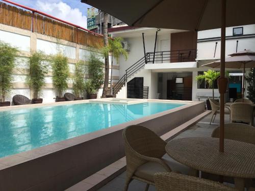土格加勞的住宿－卡梅利塔酒店，一个带椅子和桌子的游泳池以及一把遮阳伞