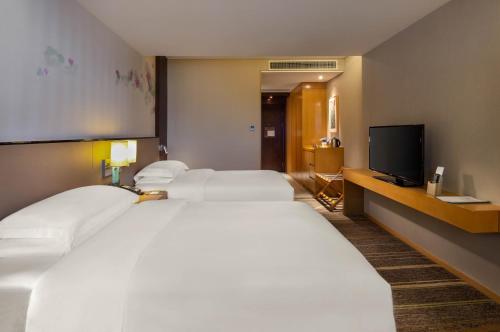 a hotel room with two beds and a flat screen tv at Hilton Garden Inn Lijiang in Lijiang