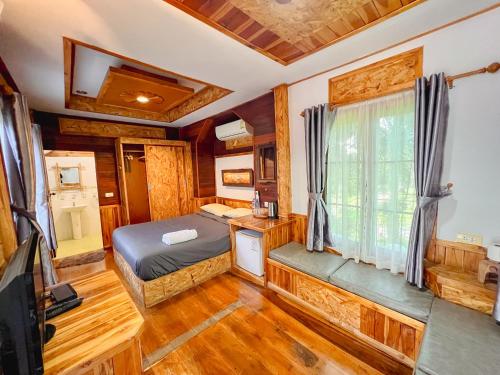 sypialnia w drewnianym domku z łóżkiem i oknem w obiekcie เนริสารีสอร์ท เขาค้อ w mieście Ban Khao Ya Nua
