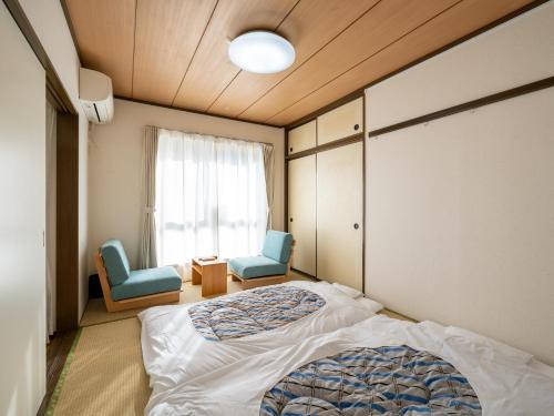 a bedroom with two chairs and a bed and a window at Vacation Inn Haneda 1 in Tokyo