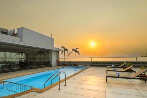 uma grande piscina com um pôr-do-sol ao fundo em Holiday Residency Coimbatore em Coimbatore