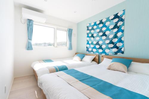 two beds in a room with blue and white at グランディオーソ沖縄プールヴィラ金武2 in Yaka