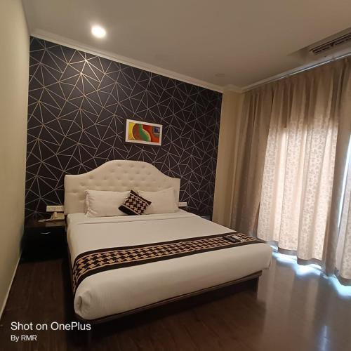 ein Schlafzimmer mit einem großen Bett und einer Wand in der Unterkunft ASTRA HOTELS & SUITES WHITEFIELD NEAR TO NALLURAHALLI METRO STATION and KTPO in Bangalore