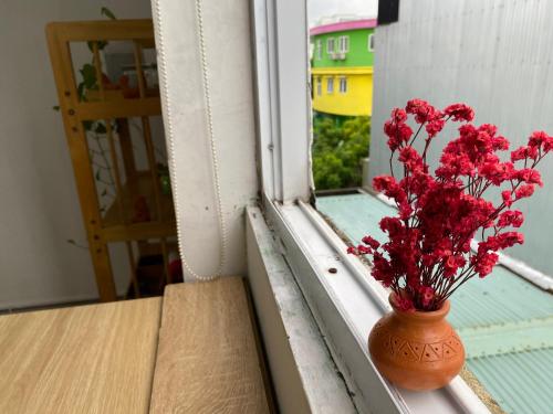a vase with red flowers sitting on a window sill at Lu Peaceful Homestay in Da Nang