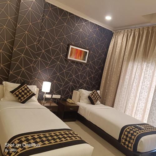 Habitación de hotel con 2 camas y pared en ASTRA HOTELS & SUITES WHITEFIELD NEAR TO NALLURAHALLI METRO STATION and KTPO en Bangalore