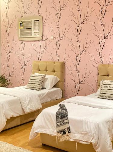 2 camas en una habitación con papel pintado de color rosa en فيلا بمسبح وحديقة خاصة en Al Ula
