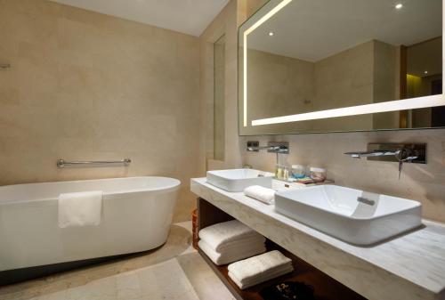 a bathroom with two sinks and a tub and a mirror at Hilton Garden Inn Lijiang in Lijiang