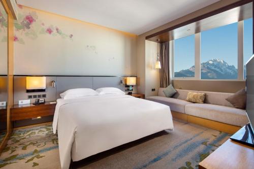 een slaapkamer met een groot wit bed en een bank bij Hilton Garden Inn Lijiang in Lijiang