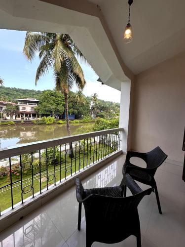 a balcony with two chairs and a palm tree at Hotel Riverside in Baga