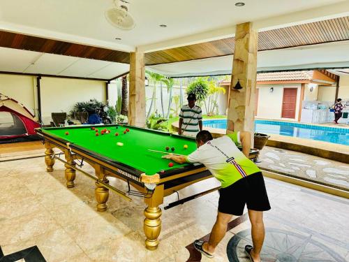 a man is playing pool on a pool table at บ้านเพื่อน 44 พลูวิวล่า in Bang Sare