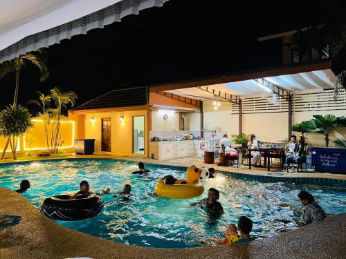 eine Gruppe von Personen in einem Schwimmbad in der Nacht in der Unterkunft บ้านเพื่อน 44 พลูวิวล่า in Bang Sare