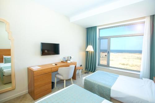 a hotel room with a desk and a bed and a window at Khazar Inji in Baku