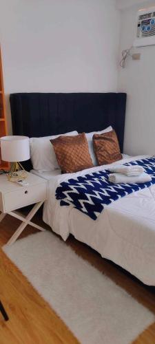 a bed with a blue and white blanket and a table at ArezzodeLaila in Davao City