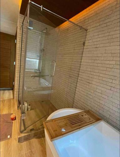 a bathroom with a shower and a bath tub at Banbangei Riverside Poolvilla in Ban Bang Rathuk