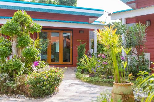 a garden in front of a red house with plants at Thai Smile Bungalows in Ko Lanta