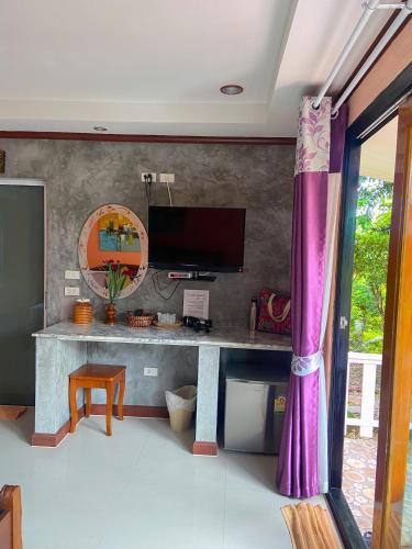 a room with a desk with a tv and a purple curtain at Thai Smile Bungalows in Ko Lanta