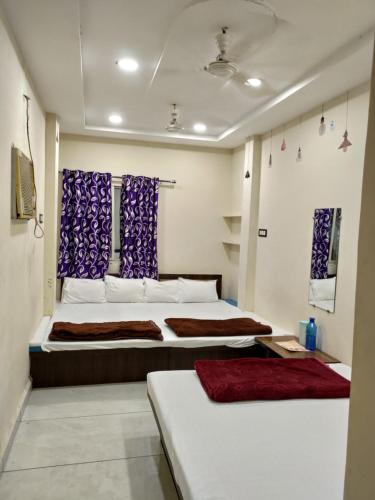 a bedroom with two beds and purple curtains at Hotel villa in Ujjain