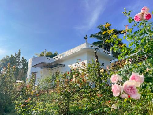 a white house with roses in front of it at เนริสารีสอร์ท เขาค้อ in Ban Khao Ya Nua