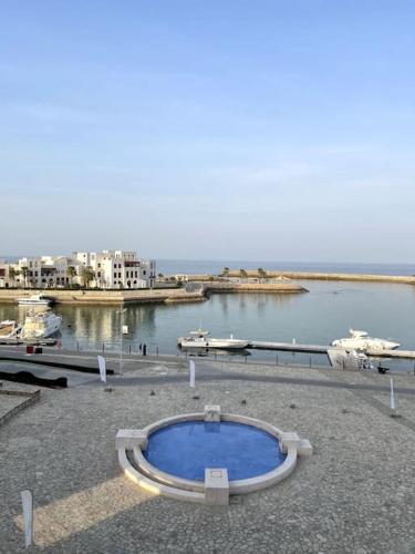 a large blue pool sitting on the side of a body of water at Jabal Sifah Tha Marina View Apartment in Muscat