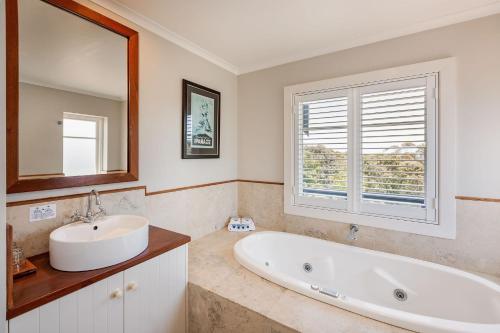 baño con bañera, lavabo y ventana en Caves House Hotel, en Yallingup